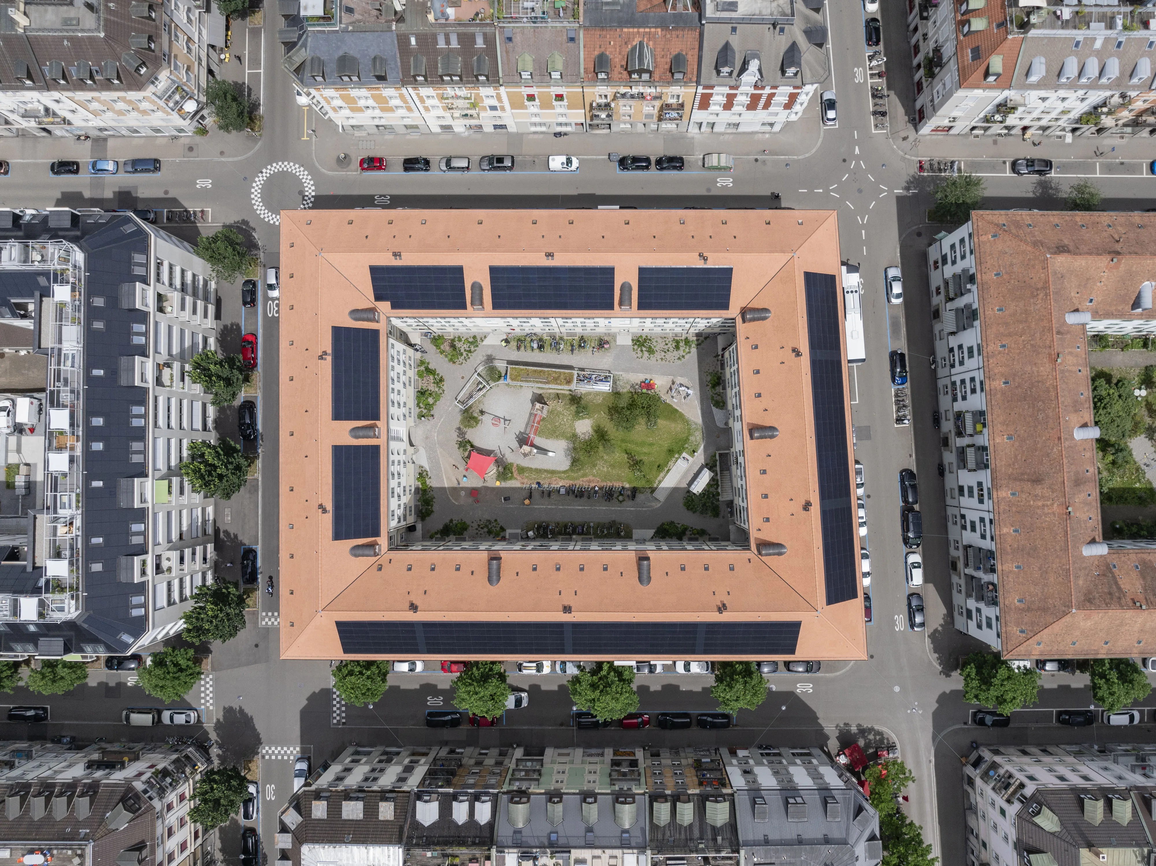 Luftaufnahme der Wohnsiedlung der GBMZ Siedlung Feld 1 in der Stadt Zürich. Der Innenhof beinhaltet Grünflächen, Spielplätze und Sitzgelegenheiten.